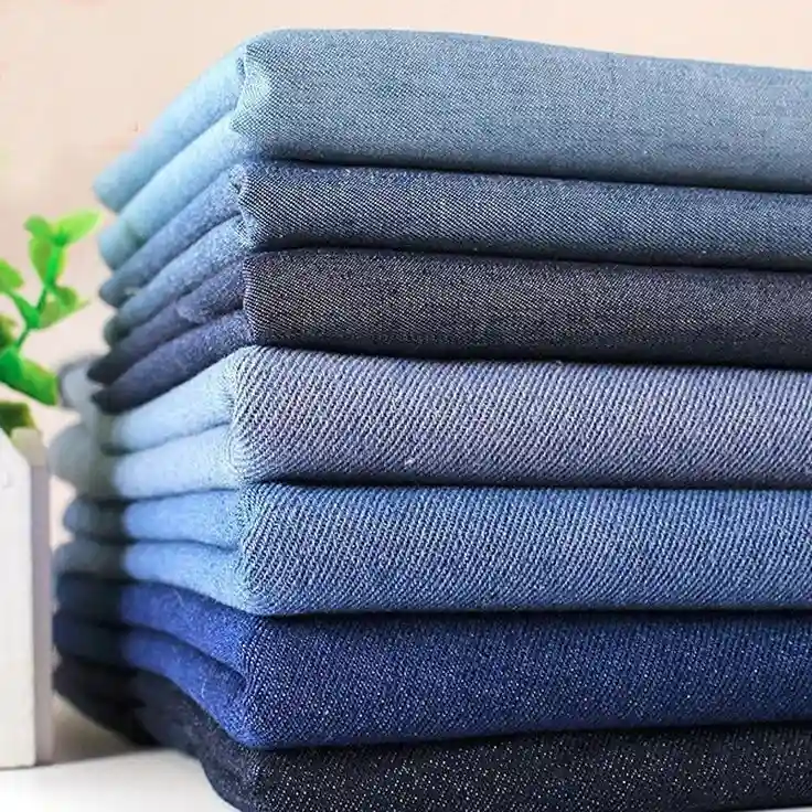 Tumpukan kain denim berbagai warna biru dan hitam, cocok untuk bahan jaket berkualitas dan tahan lama.